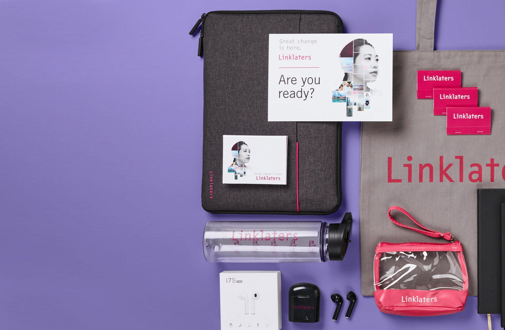 Collection of branded merchandise products such as tote bags and water bottles against purple backdrop.