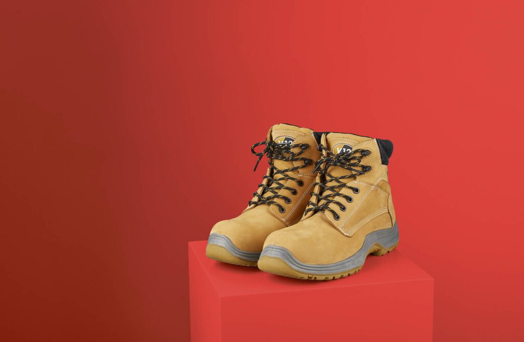 Workboots on plinth against red background